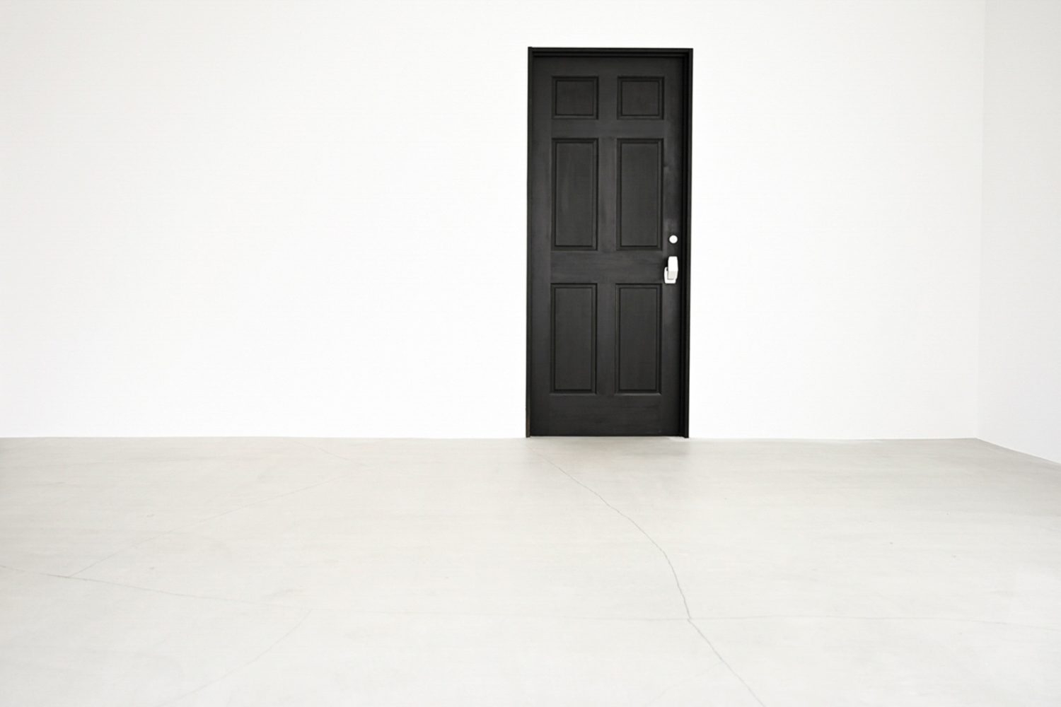 黒いドアの左右に広がる真っ白な壁