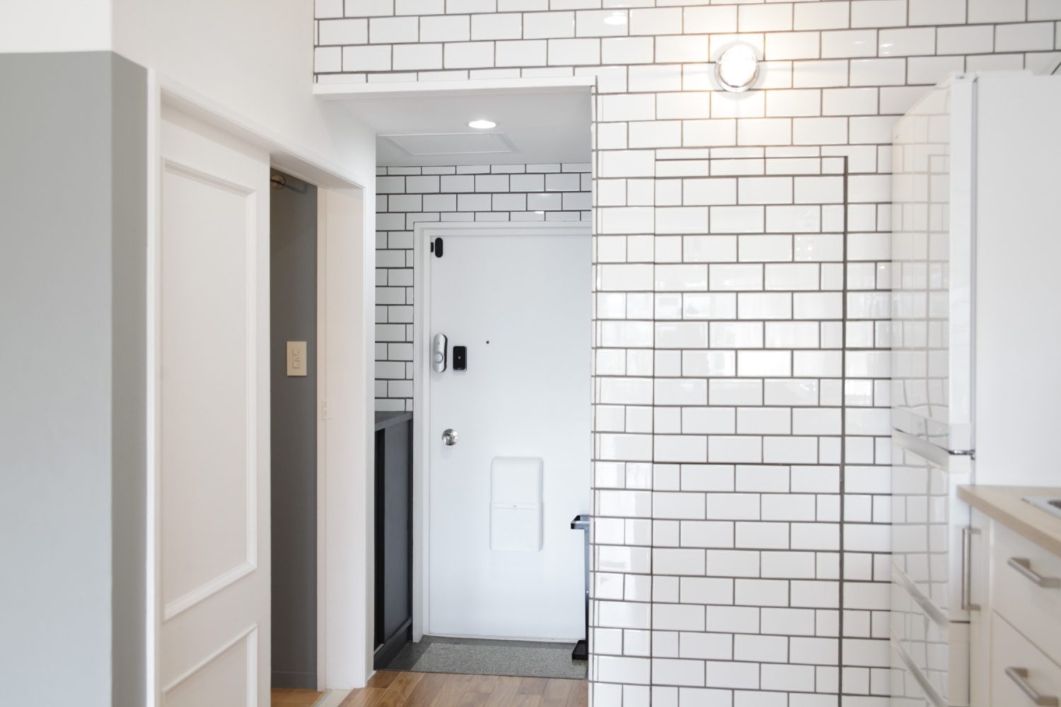 キッチンから続く白タイルを基調とした玄関