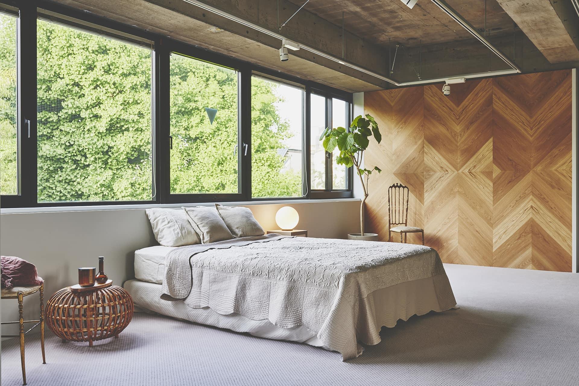 東側の窓から光が入るカーペット床と木壁のベッドルーム