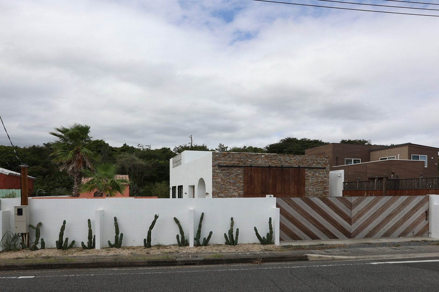 木の模様が目を惹く門扉 / 白い外壁と植物