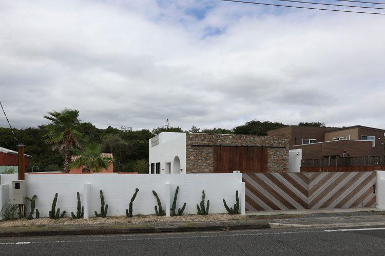 木の模様が目を惹く門扉 / 白い外壁と植物