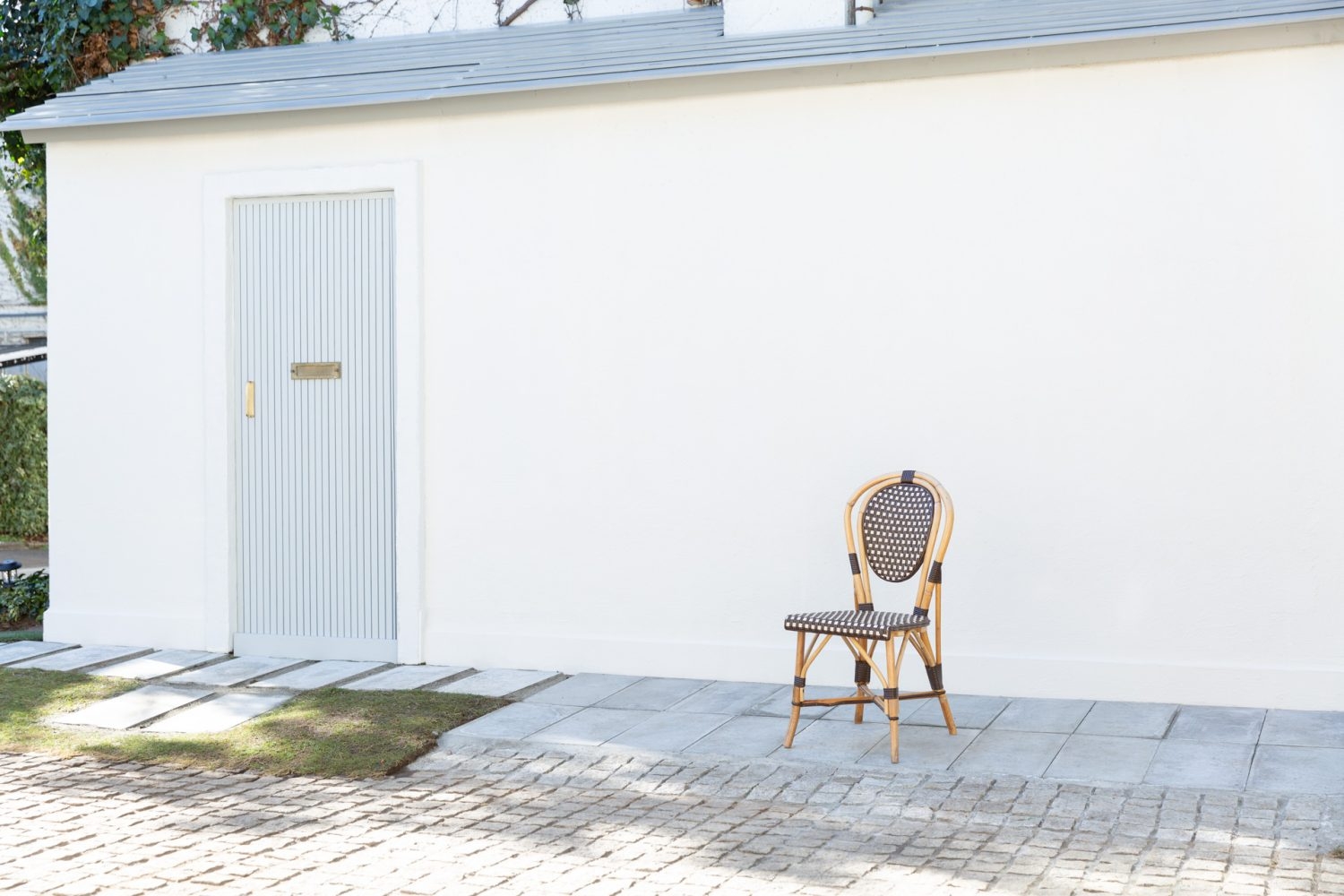 建物の向かいの白壁と淡い色の扉