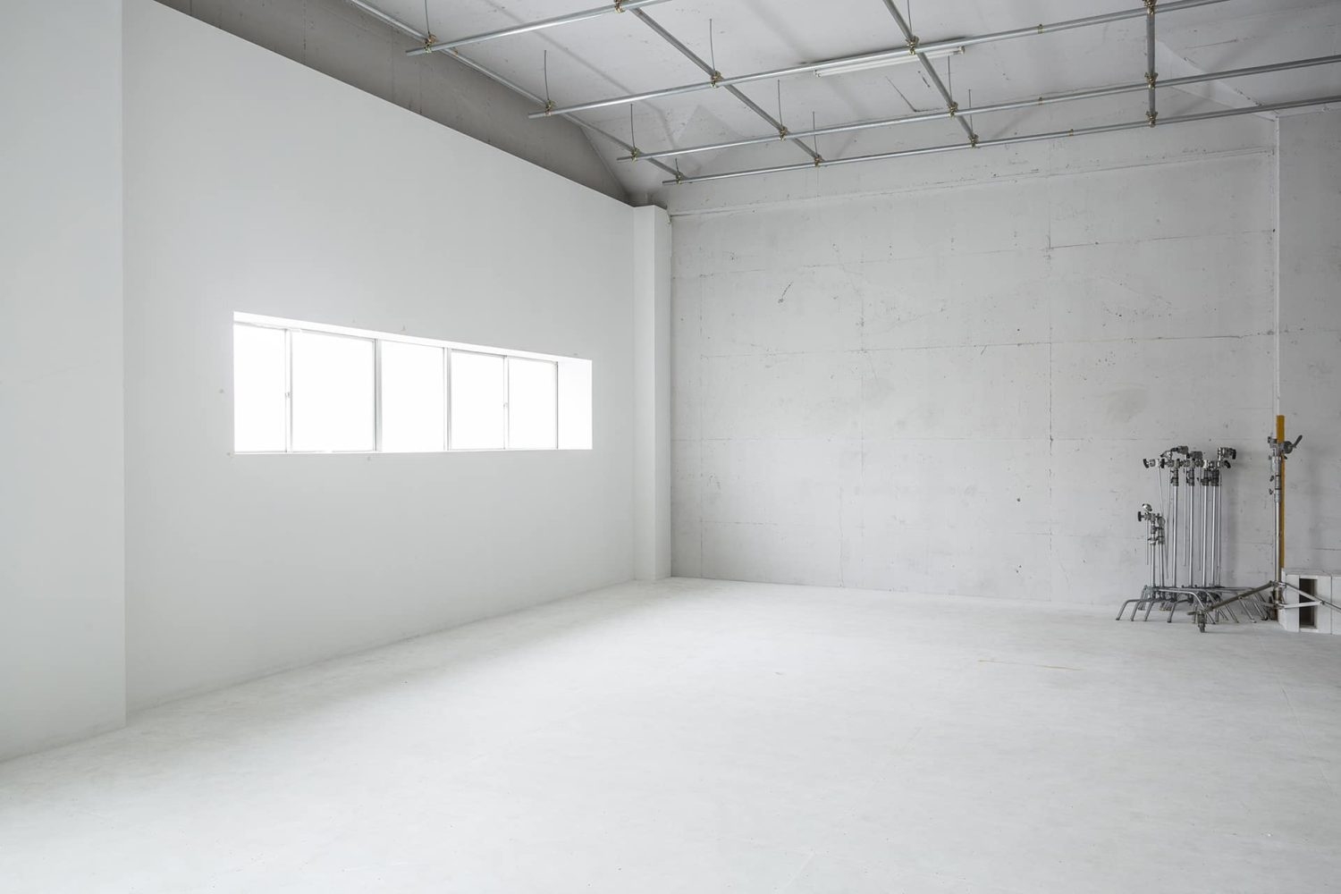 柔らかい自然光が差し込む白壁とコンクリート床