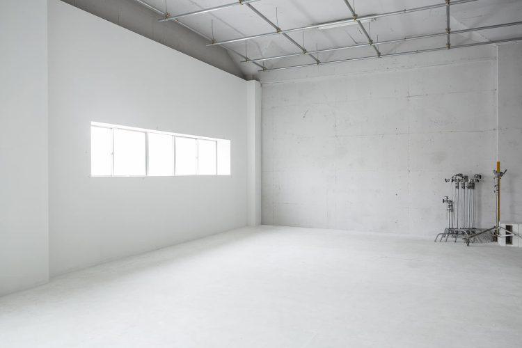柔らかい自然光が差し込む白壁とコンクリート床