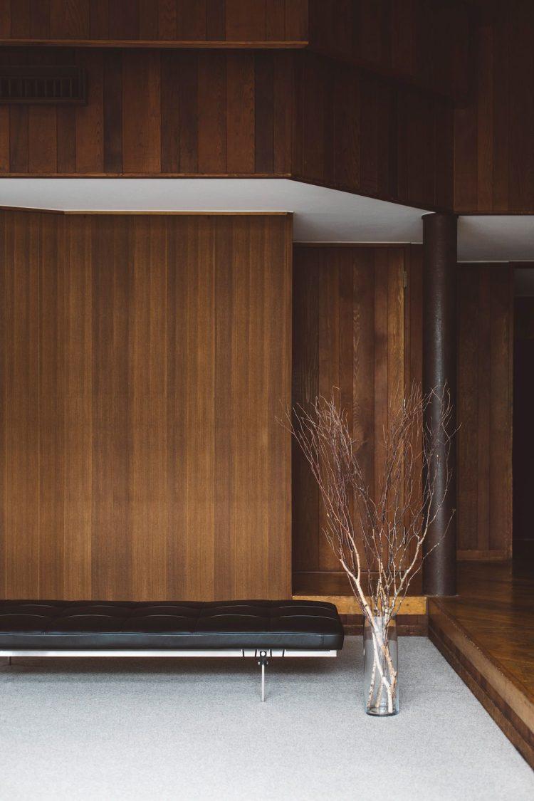 大きな枝物、革張りのソファが映える木壁