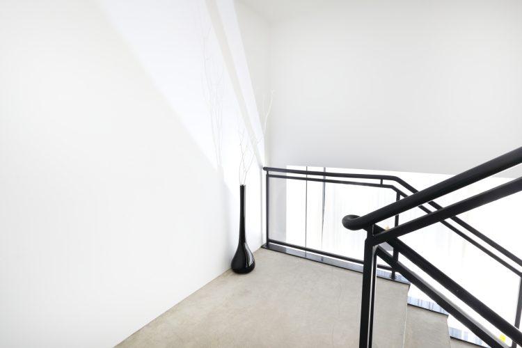 吹き抜け階段の踊り場はシンプルな白壁