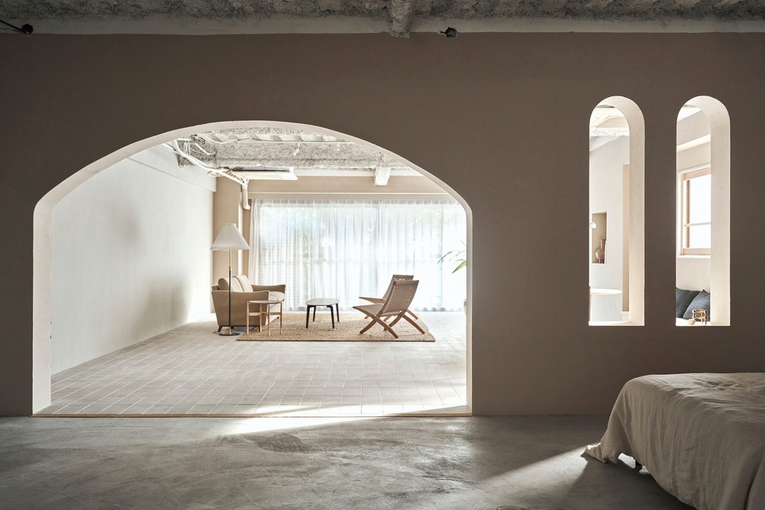 アーチ壁で繋がるふたつの空間はタイル床とモルタル床の異なる質感