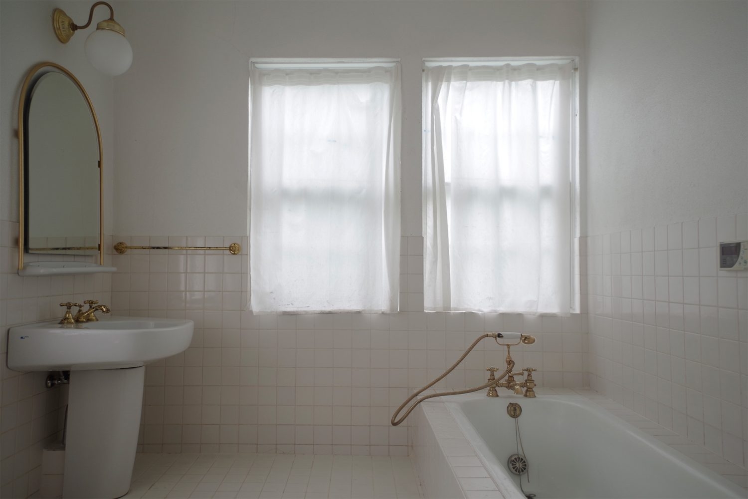 白タイルにゴールドの差し色が添えられたバスルーム