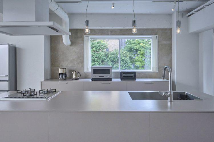 被写体と調和するカラーのキッチンと石目調の背景壁