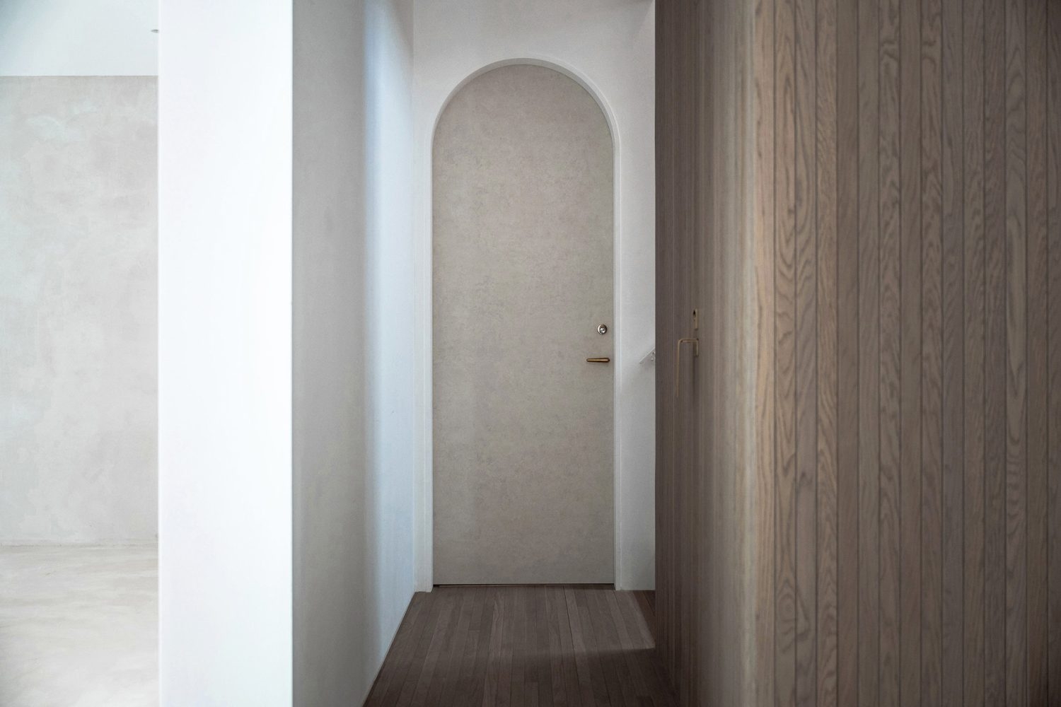 階段踊り場からやわらかく光が落ちるアーチ扉