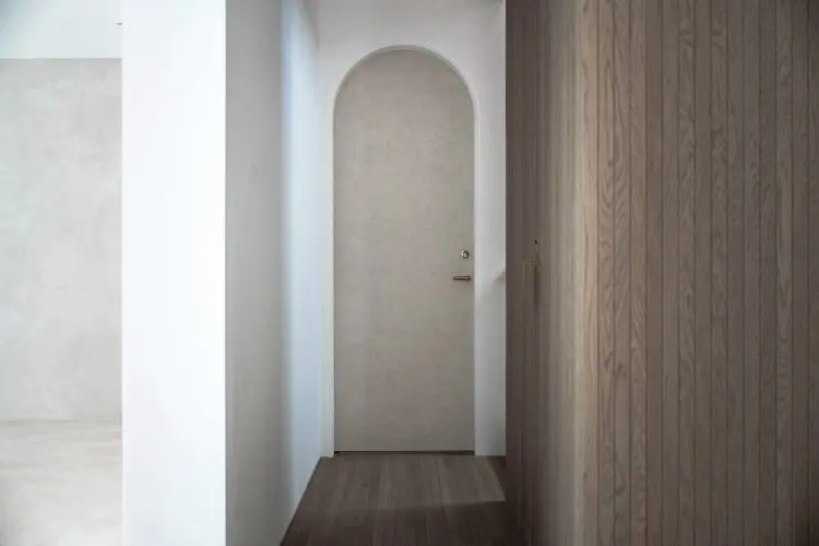 階段踊り場からやわらかく光が落ちるアーチ扉