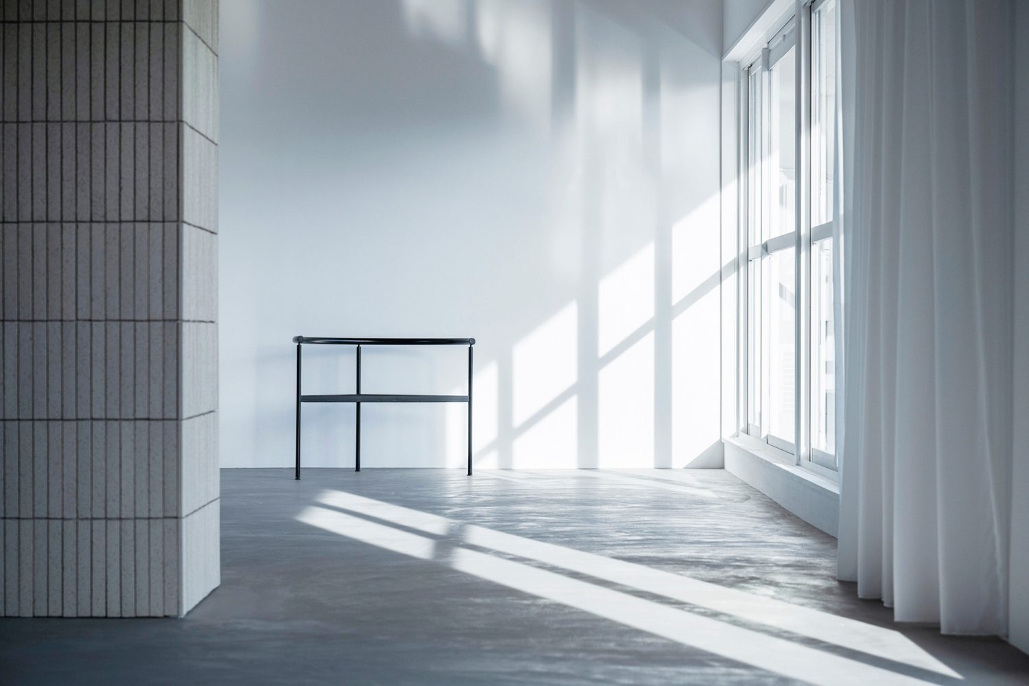 大きな窓越しに落ちるサイド光と白い壁