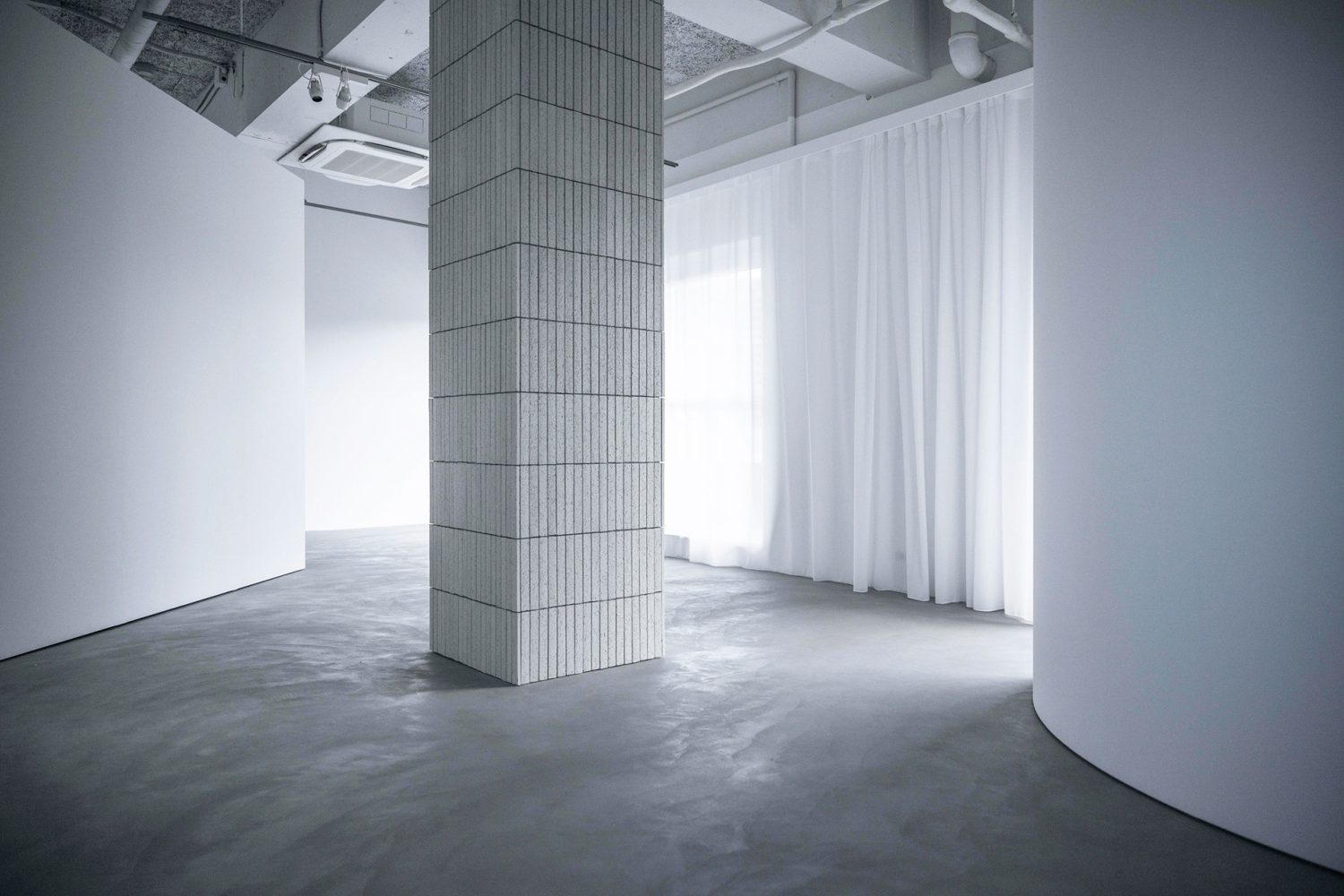 マットなグレーモルタル床とシアーカーテン