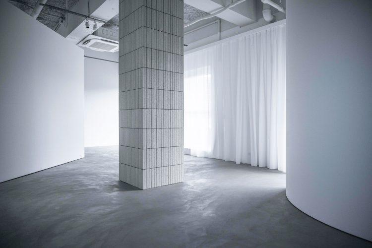 マットなグレーモルタル床とシアーカーテン