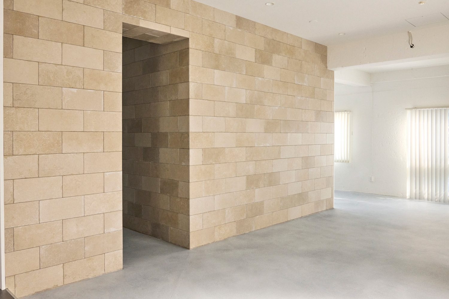 ベージュの石材タイル壁と開口が印象的
