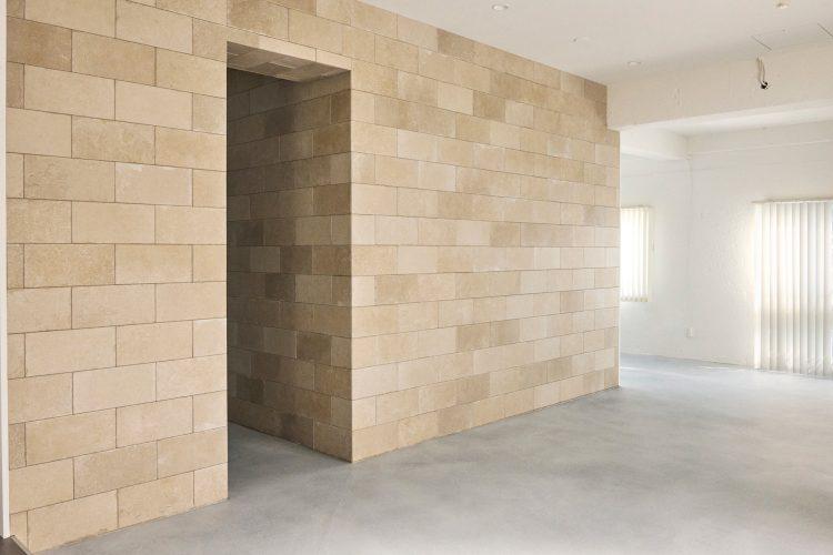 ベージュの石材タイル壁と開口が印象的