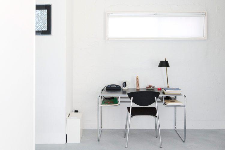 白壁に向かって配置された無機質なデスク