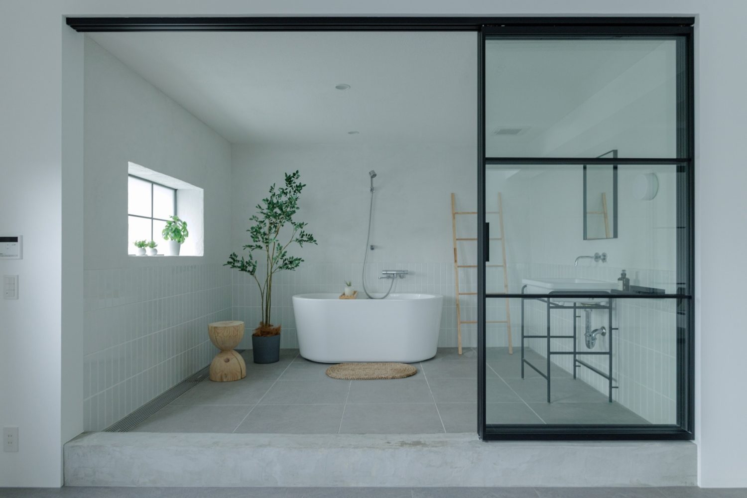 光が入る壁床タイル仕上げのバスタブ・洗面スペース