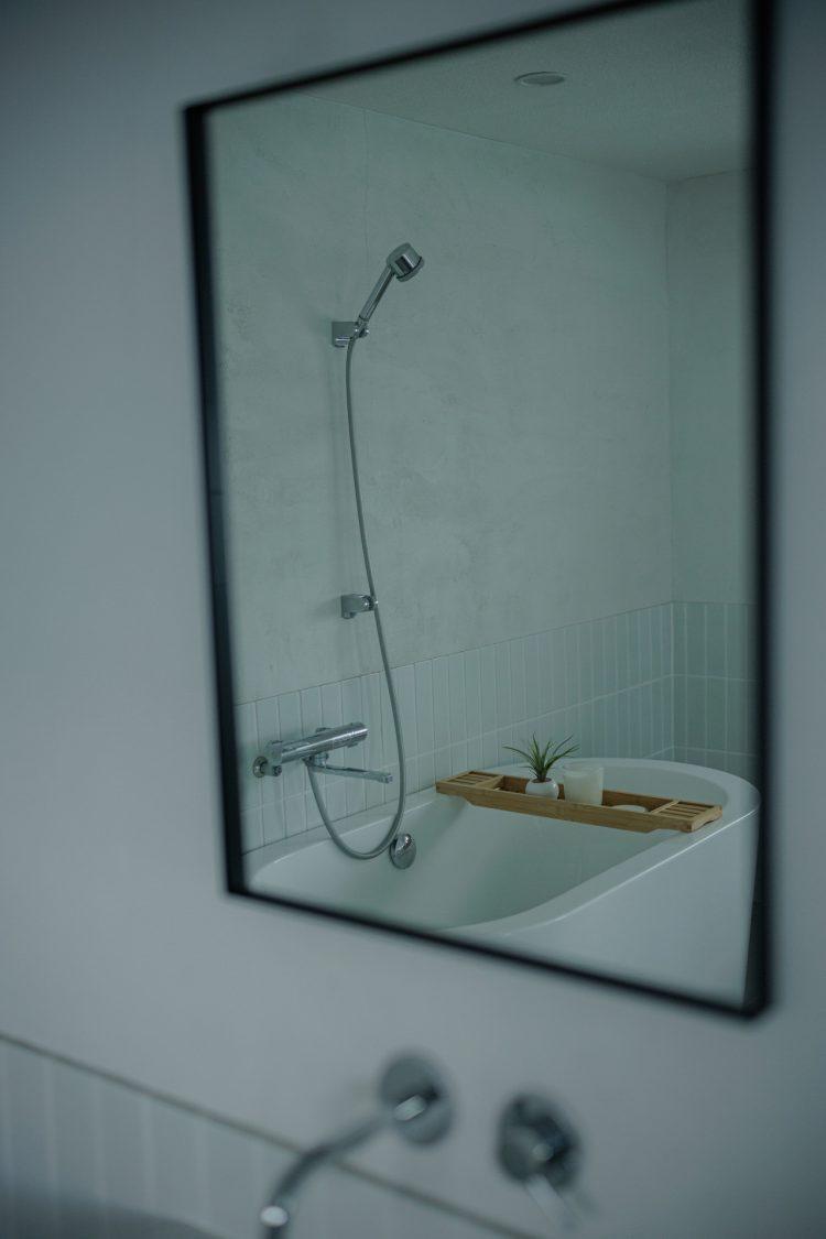 洗面の鏡に映るシャワーとバスタブ