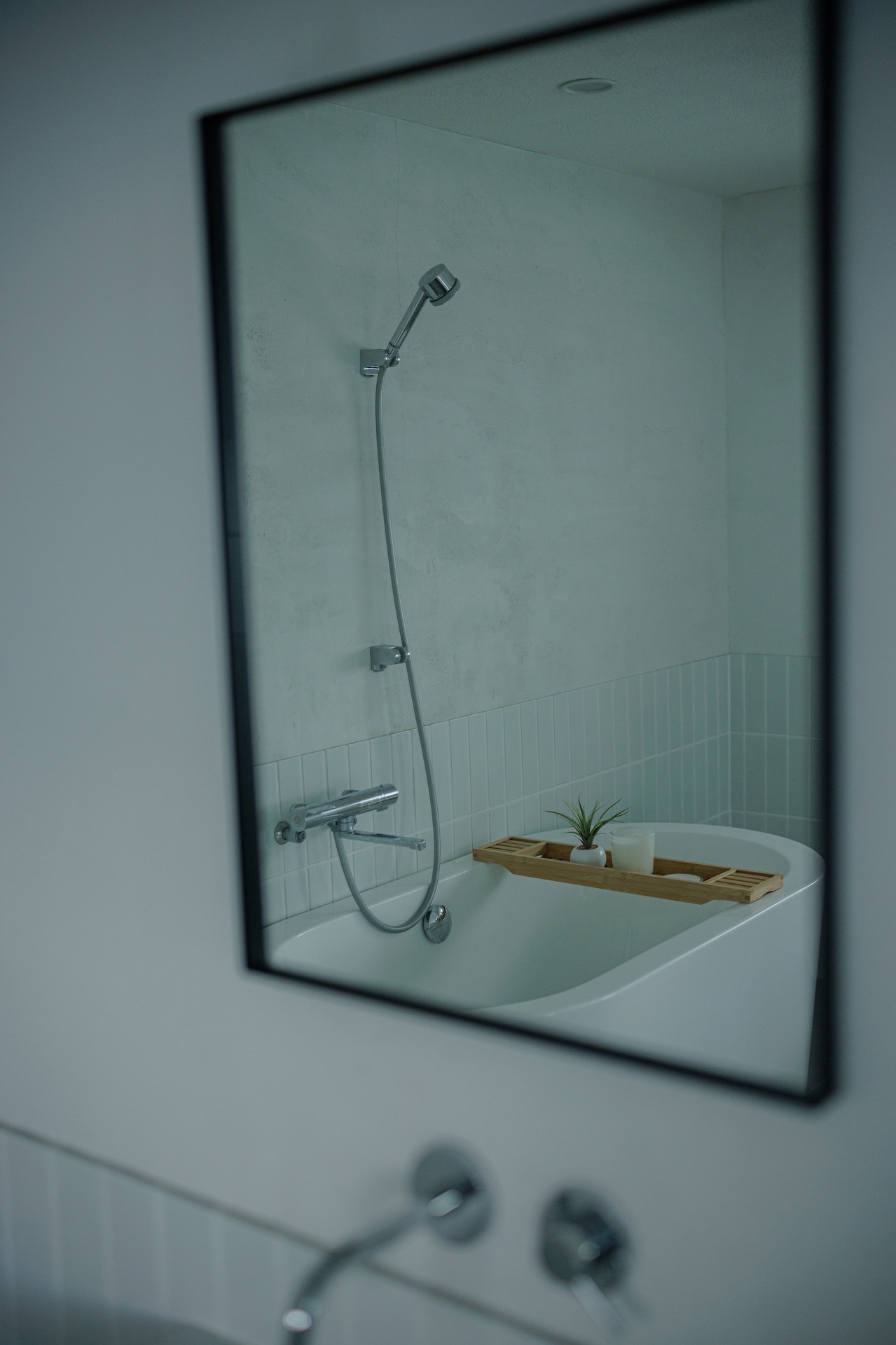 洗面の鏡に映るシャワーとバスタブ