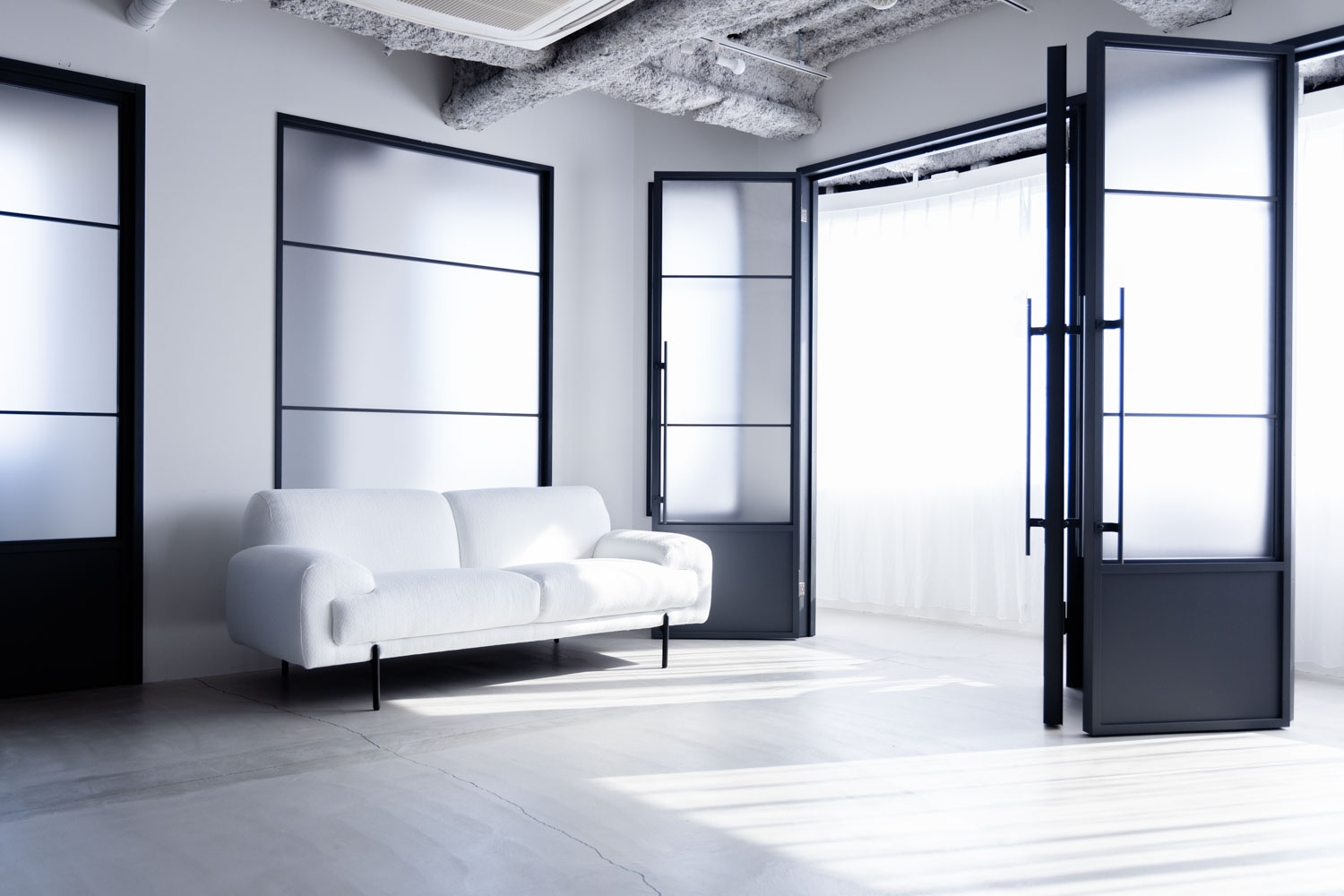 黒窓と白ソファのモノクロシーン