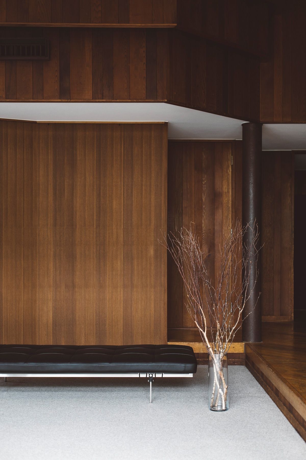 大きな枝物、革張りのソファが映える木壁