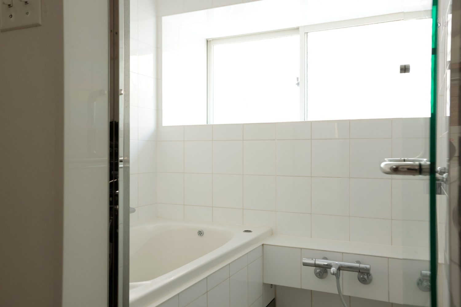 白いタイル張り・ガラス扉のバスルーム